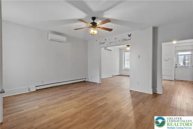 a view of an empty room with wooden floor and a ceiling fan