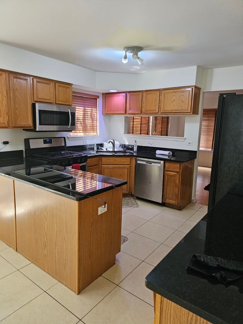 847 Teasel Lane Aurora, IL 60504 - Photo 6 of 19 a kitchen with stainless steel appliances granite countertop a stove a sink and a microwave