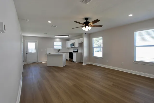a view of an empty room with a kitchen and wooden floor