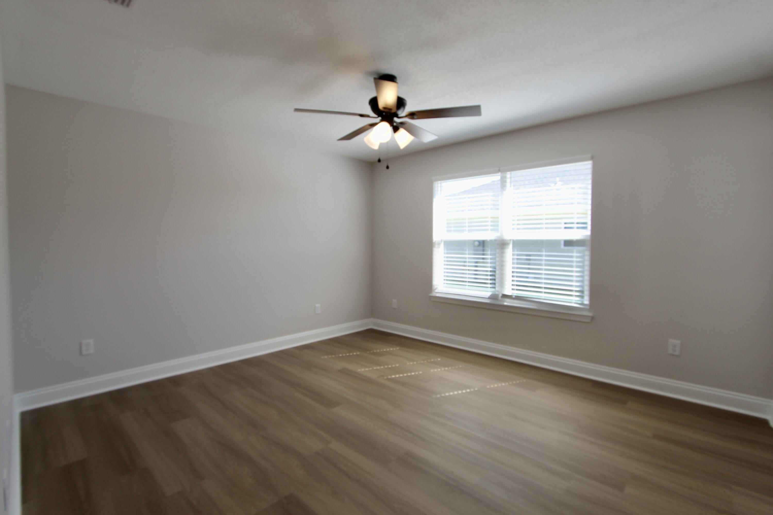 4610 Bobolink Way Crestview, FL 32539 - Photo 9 of 25 an empty room with wooden floor ceiling fan and windows