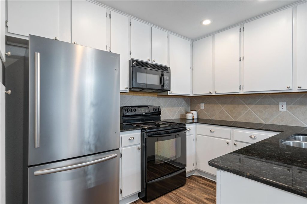1748 Ohlen Road, Unit 76 Austin, TX 78757 - Photo 15 of 34 a kitchen with stainless steel appliances granite countertop a refrigerator a stove a sink and a microwave