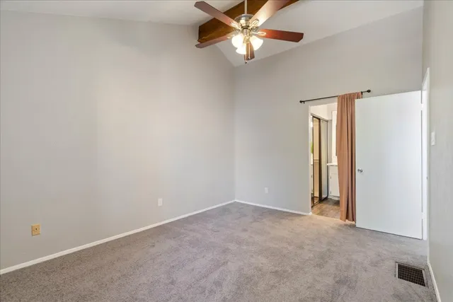 an empty room with a chandelier fan and windows