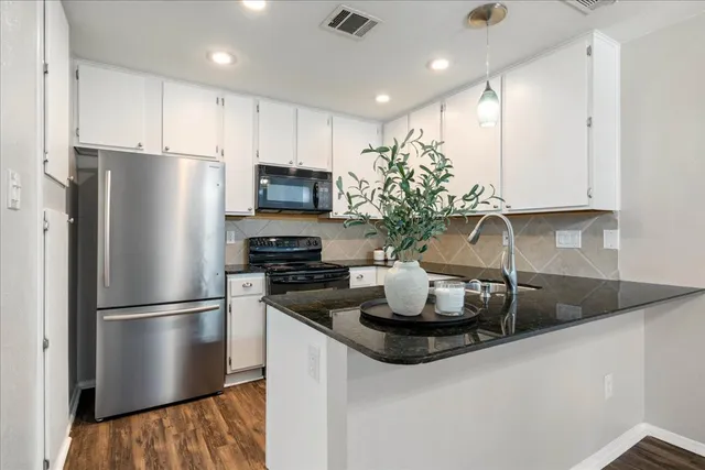 a view of an empty room with wooden floor and a fireplace