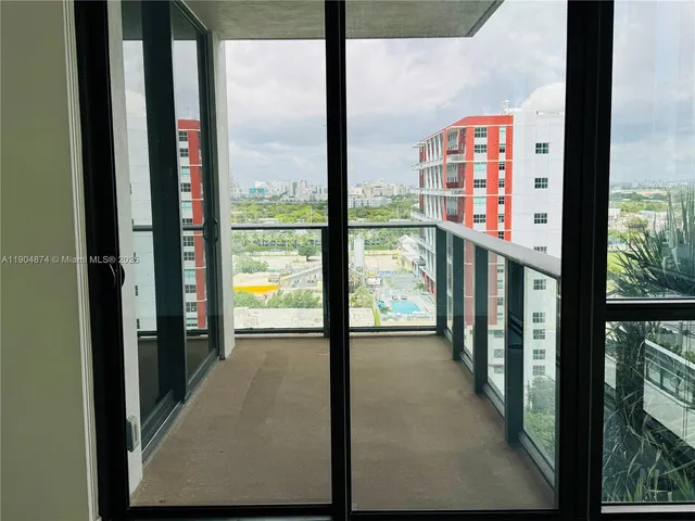 a view of an empty room with wooden floor and windows