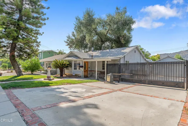 a view of a house with a yard and large trees