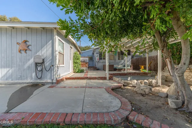 a view of a house with brick walls plants and large tree