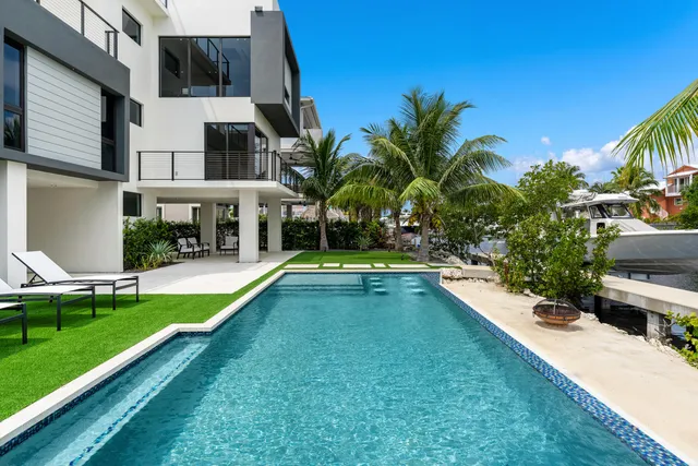 a view of a small white house with a yard and sitting area