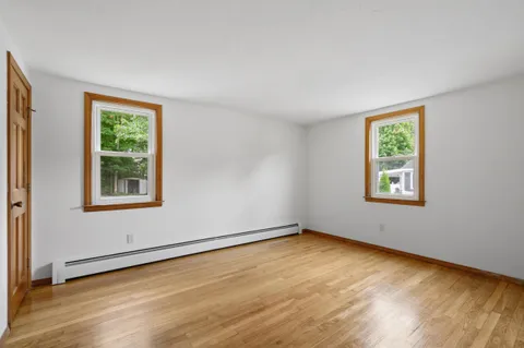 a view of an empty room with a window and wooden floor