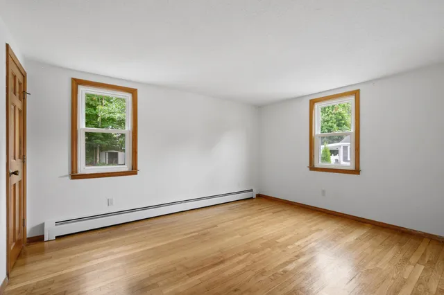 a view of an empty room with a window and wooden floor