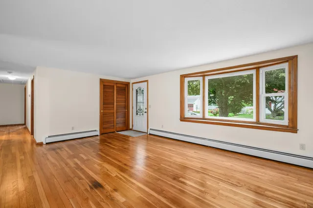 a view of an empty room with wooden floor and a window