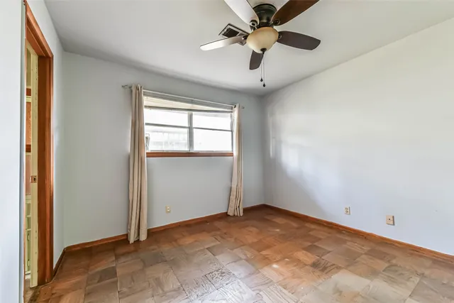 an empty room with chandelier fan and windows