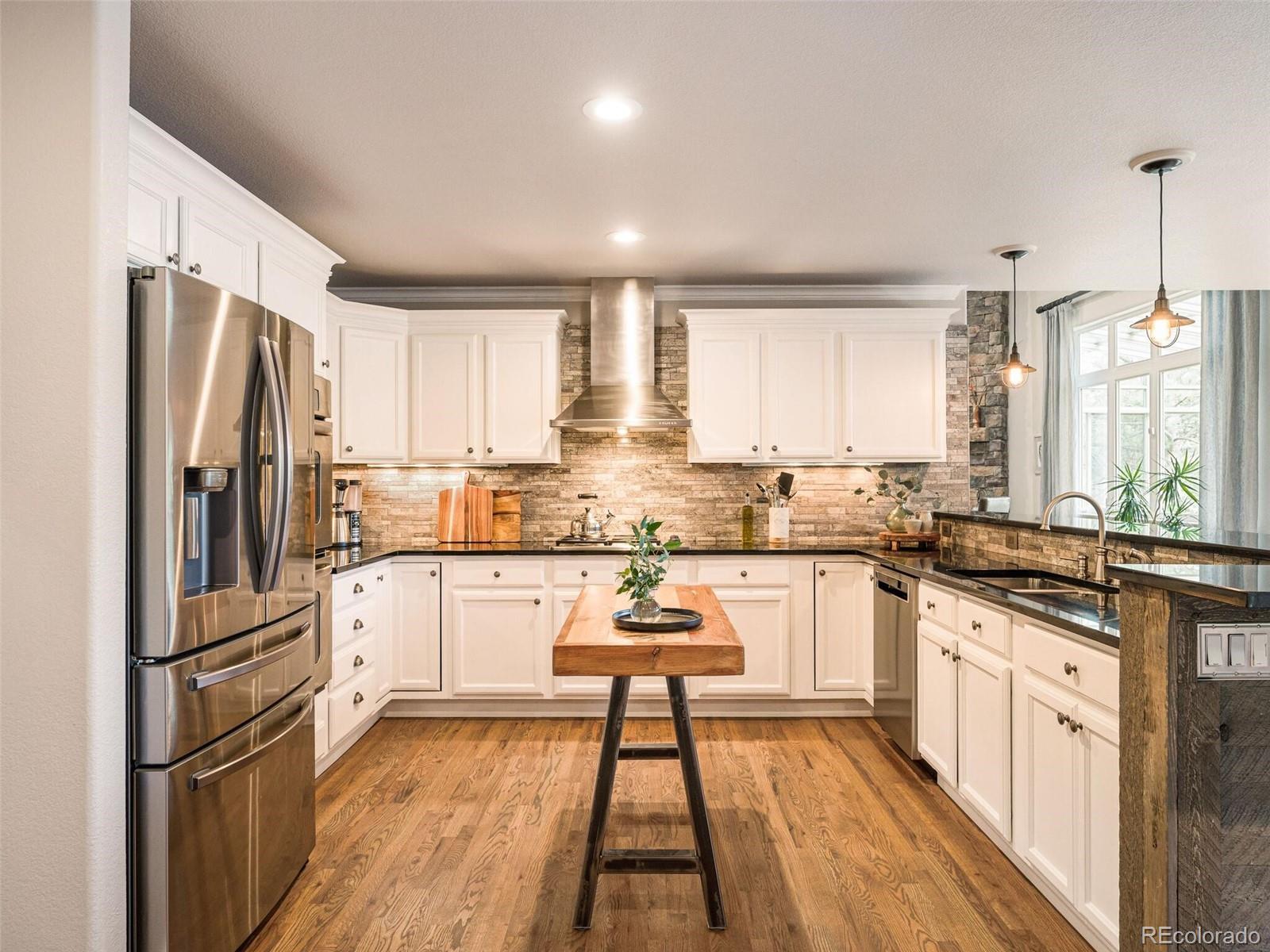 137 Nuthatch Road Evergreen, CO 80439 - Photo 22 of 50 a kitchen with a refrigerator a stove and white cabinets with wooden floor