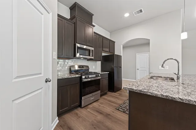 a large kitchen with granite countertop a sink and a stove top oven