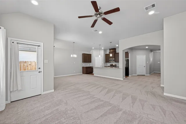 an empty room with ceiling fan and windows