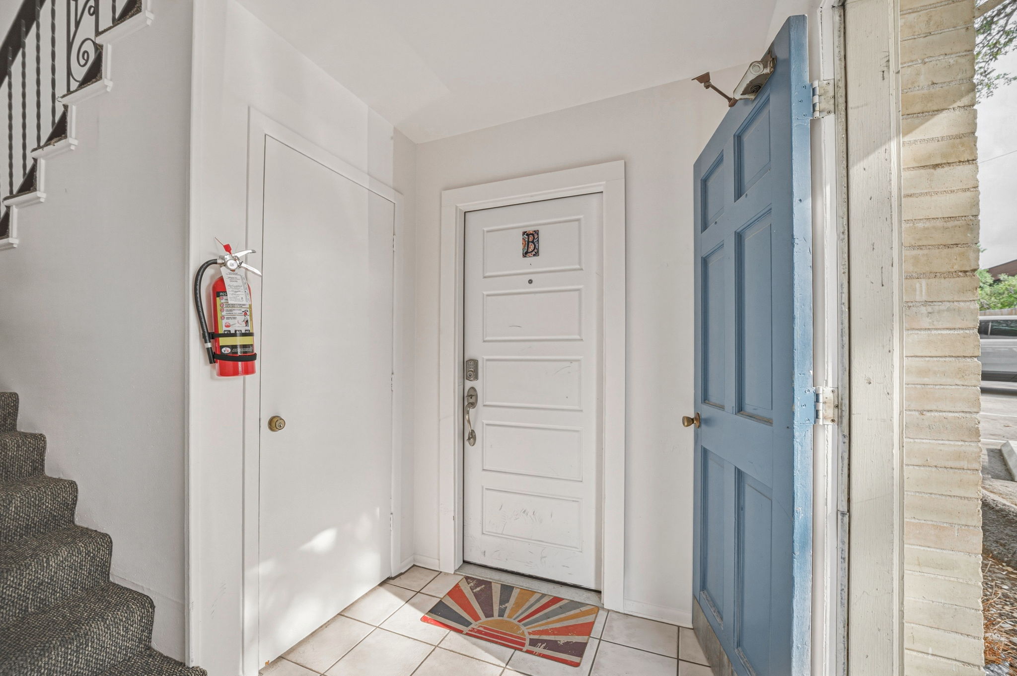 5332 Balcones Drive, Unit B Austin, TX 78731 - Photo 3 of 15 Entryway featuring light-colored tile flooring, a paneled white door, and a partially open blue door