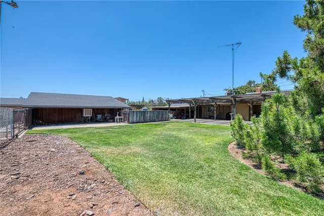 an empty room with wooden floor a ceiling fan and kitchen view