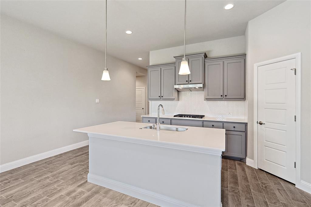 2217 Yellowhammer Road Denton, TX 76205 - Photo 16 of 30 a kitchen with kitchen island a sink and wooden floor