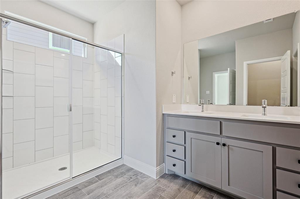 2217 Yellowhammer Road Denton, TX 76205 - Photo 23 of 30 a bathroom with a granite countertop sink a mirror and a shower