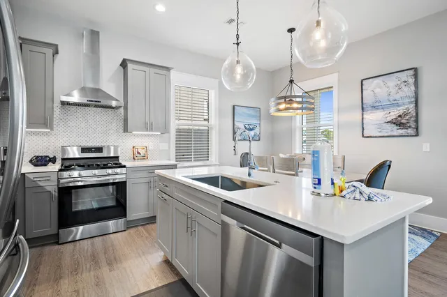 a kitchen with a sink stainless steel appliances a chandelier and wooden floor