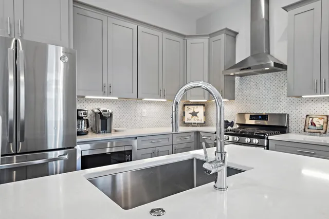 a kitchen with stainless steel appliances granite countertop a refrigerator a stove and white cabinets with wooden floor