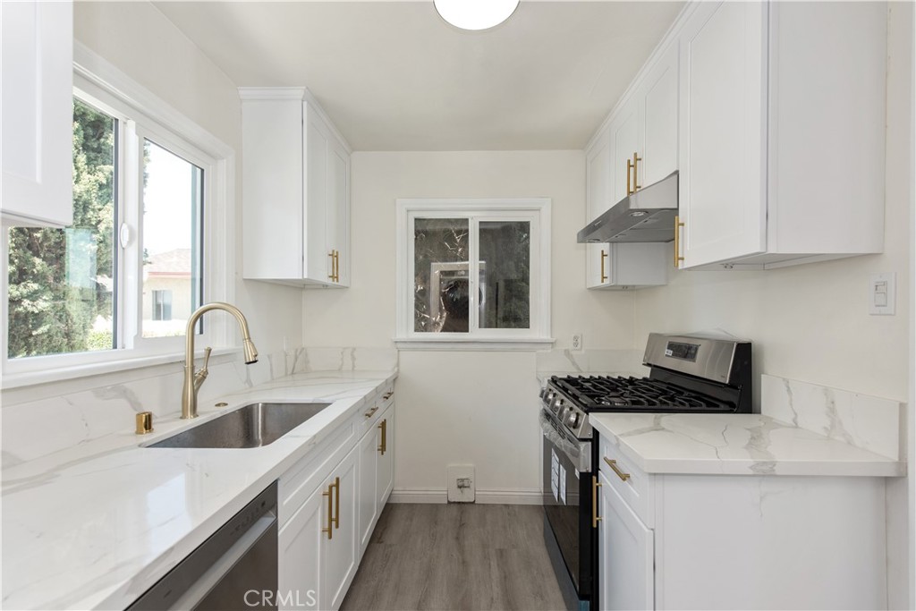 8713 Alondra Boulevard Paramount, CA 90723 - Photo 7 of 41 a kitchen with a sink a stove a microwave and cabinets
