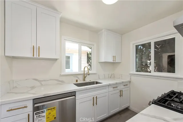 a kitchen with stainless steel appliances granite countertop a sink a stove and a granite counter tops with white cabinets