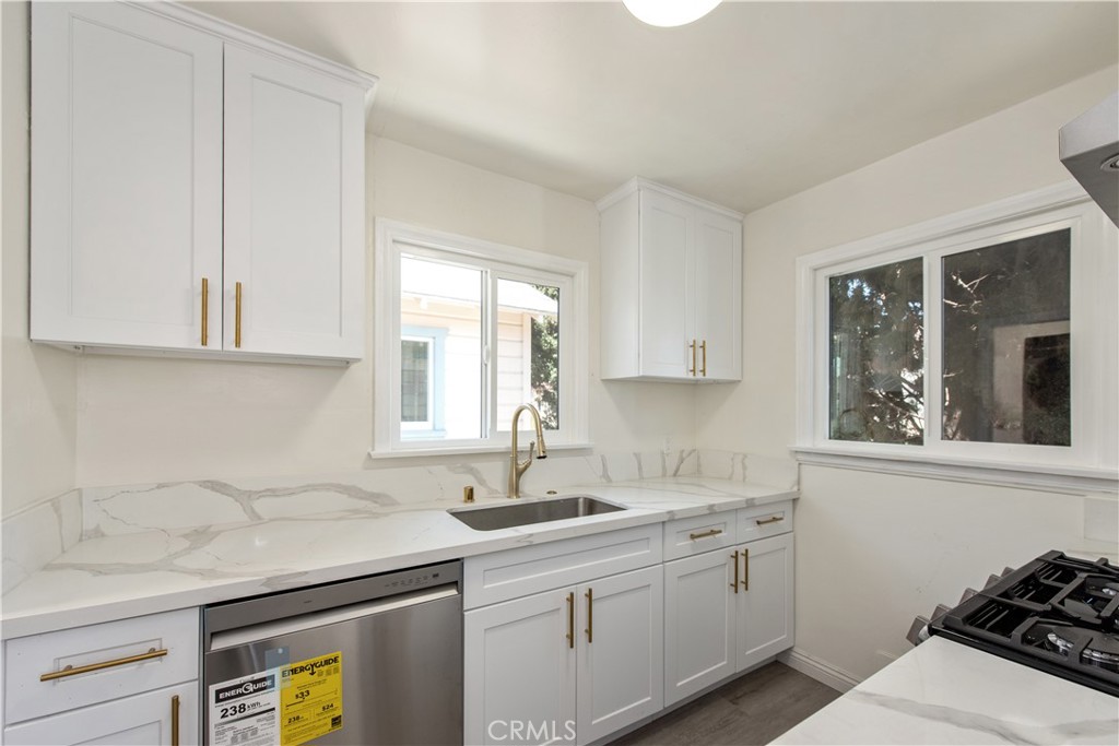 8713 Alondra Boulevard Paramount, CA 90723 - Photo 8 of 41 a kitchen with stainless steel appliances granite countertop a sink a stove and a granite counter tops with white cabinets