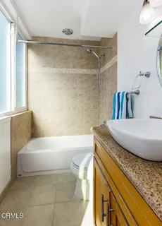 a bathroom with a granite countertop sink a toilet a mirror and bathtub