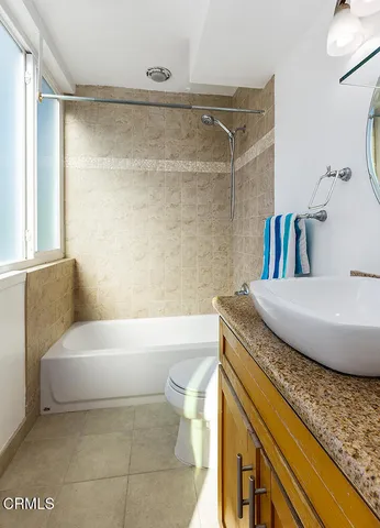 a bathroom with a granite countertop sink a toilet a mirror and bathtub