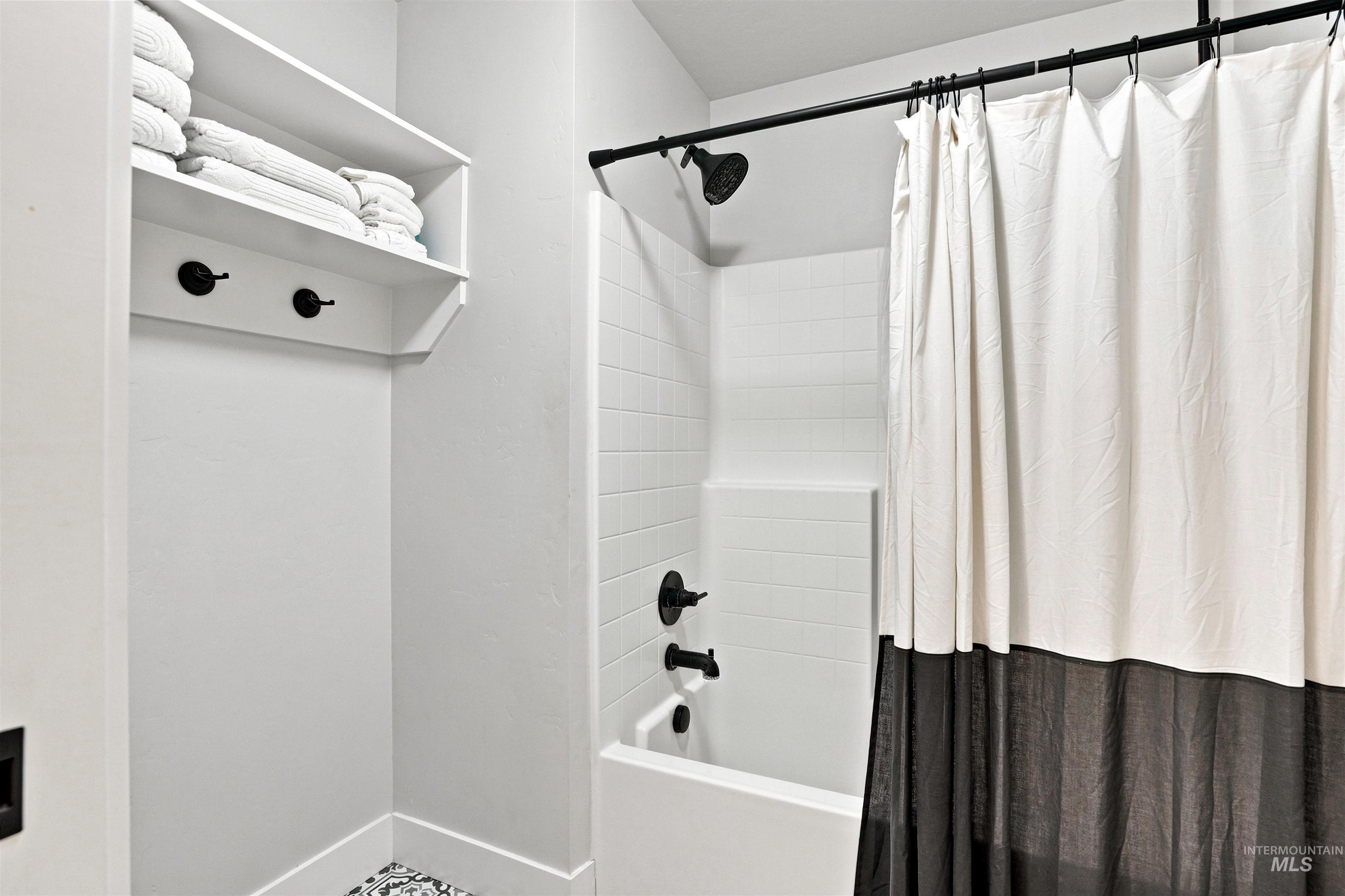 4323 West Ladle Rpds Drive Meridian, ID 83646 - Photo 33 of 49 Bathroom featuring a clean white bathtub/shower combination with subway tile surround, dark bronze fixtures, and a built-in shelving unit with hooks