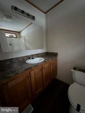 a bathroom with a granite countertop sink and a toilet