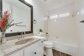 a bathroom with a granite countertop sink a toilet and shower
