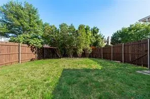 a view of a backyard with large trees and wooden fence