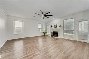 a view of a livingroom with a fireplace a ceiling fan and windows