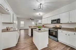 a kitchen with kitchen island granite countertop a sink cabinets and wooden floor