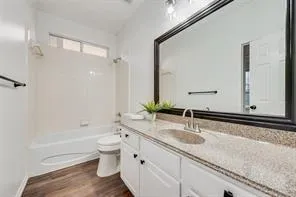 a bathroom with a granite countertop sink a toilet and a large mirror