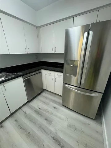 an empty room with wooden floor cabinet and windows