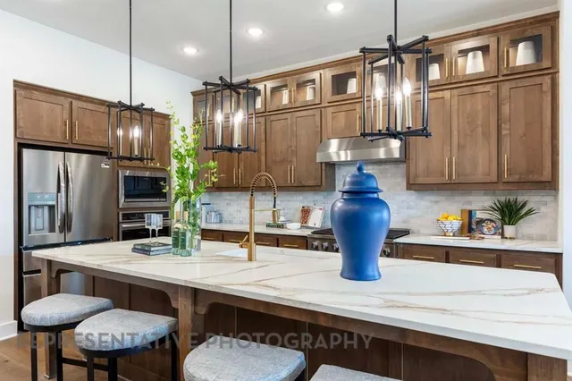 a kitchen with stainless steel appliances kitchen island granite countertop a refrigerator a sink and wooden cabinets
