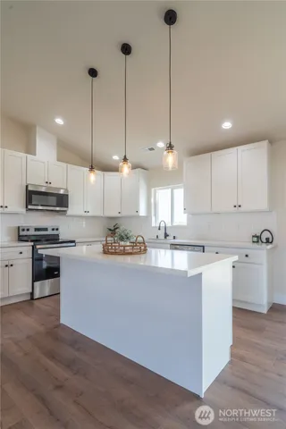 a kitchen with kitchen island a counter top space a sink stainless steel appliances and cabinets