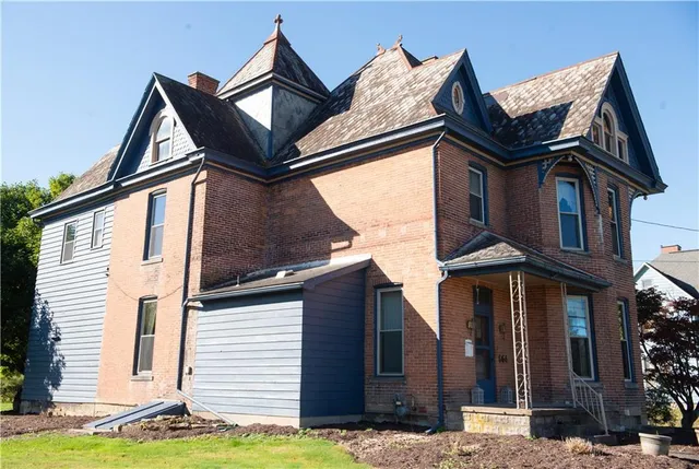 a view of a white house with a small yard and plants