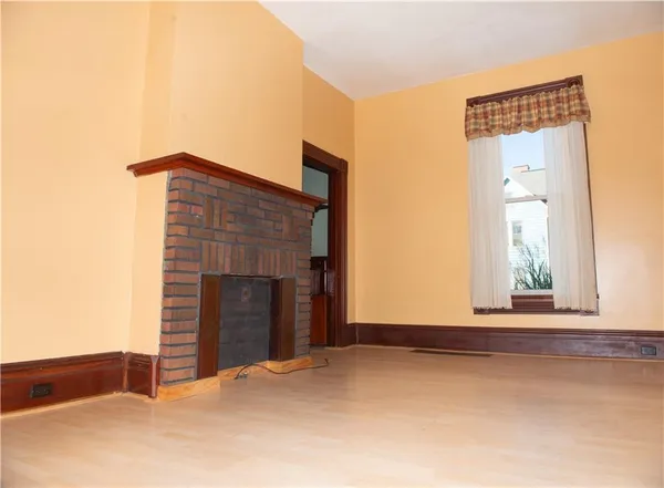 a view of an empty room with window and fire place