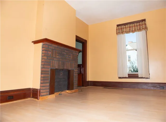 a view of an empty room with window and fire place