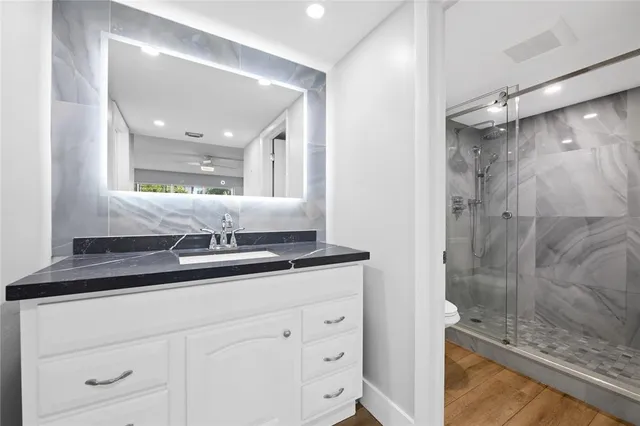 a bathroom with a granite countertop sink a mirror and shower