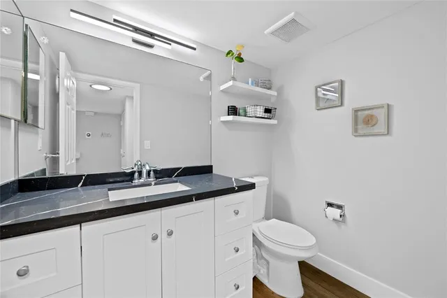 a bathroom with a granite countertop sink mirror vanity and toilet