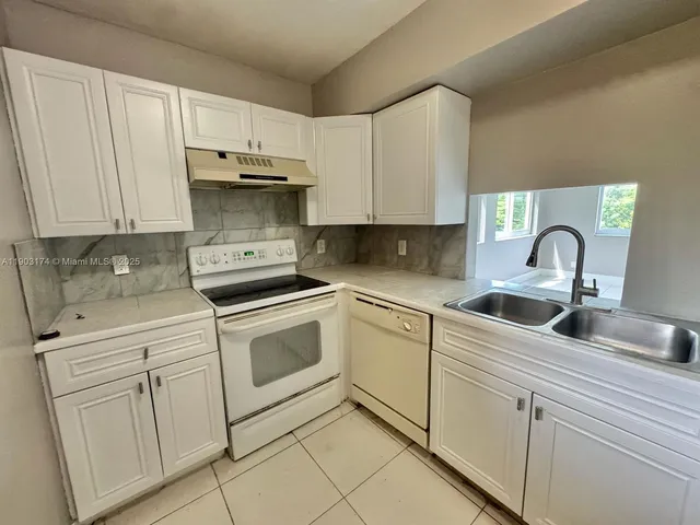 a kitchen with white cabinets and white appliances