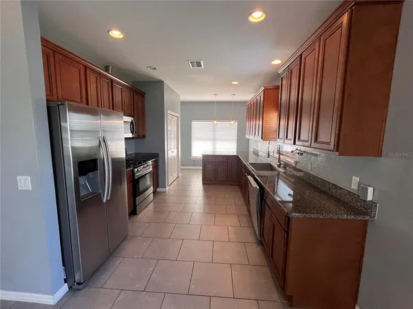 a kitchen with stainless steel appliances granite countertop a refrigerator a sink a stove and island