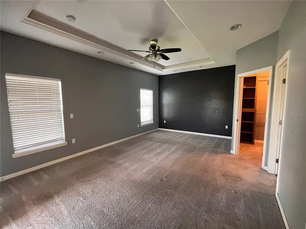an empty room with windows and fan