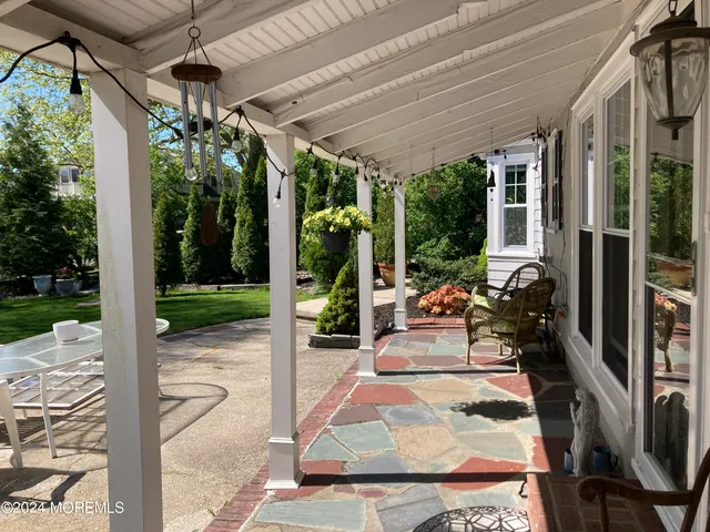 a view of a patio with table and chairs floor to ceiling window and garden