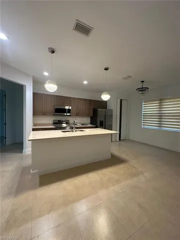 a large kitchen with kitchen island a sink a stove a refrigerator and white cabinets