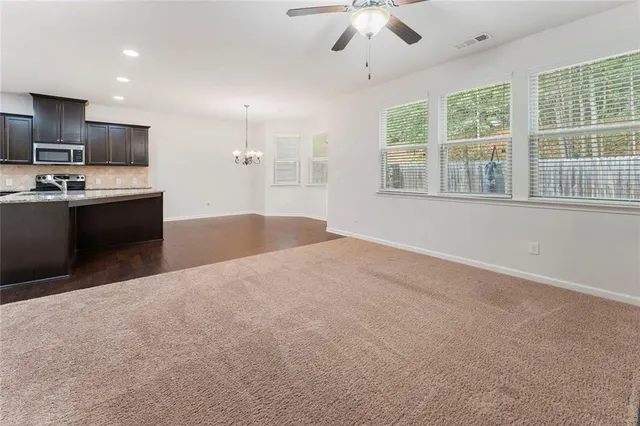 a large white kitchen with kitchen island a large counter top space appliances and a chandelier